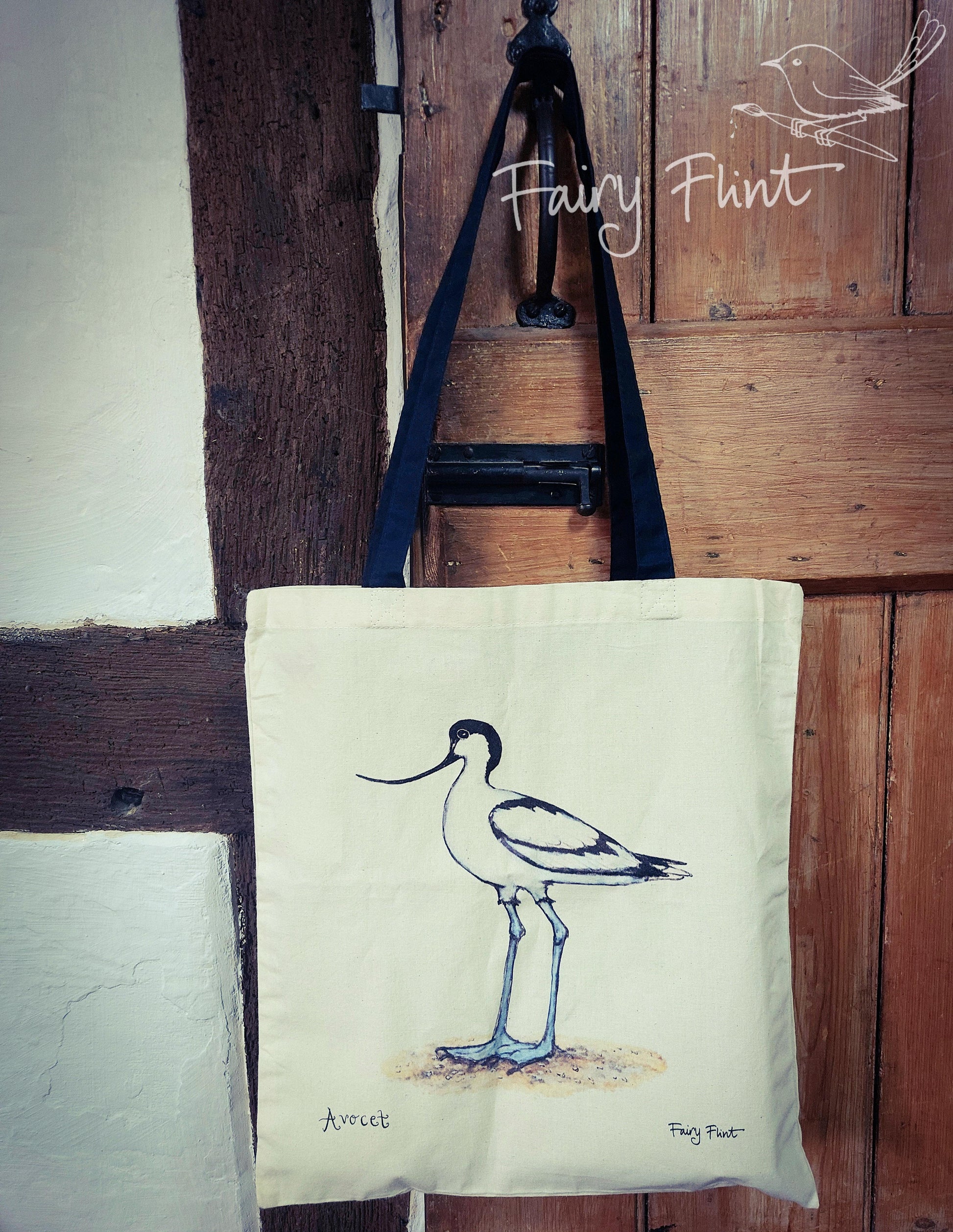 Canvas bag with Avocet painting eco friendly print by Fairy Flint photoshoot in cruck frame 15th century cottage, bag hanging on door latch of wooden door next to wall with oak beams