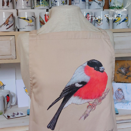 Organic Apron with Bullfinch painting by Fairy Flint printed with eco friendly inks, apron hung on mannequin in front of other aprons with birds, moorhens, ducks and swans on