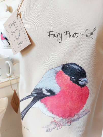 Organic Apron with Bullfinch painting by Fairy Flint printed with eco friendly inks, apron hung on mannequin 