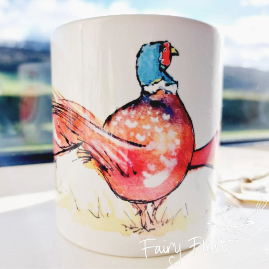 Ceramic mug with Pheasant painting design by Fairy Flint photoshoot at Eaton Manor Shropshire Wenlock Edge behind mug