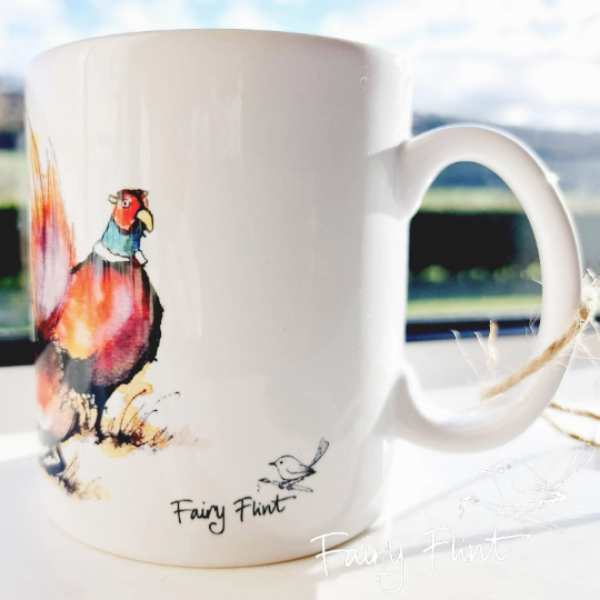 Ceramic mug with eco print of a fun Pheasant painting design by Fairy Flint photoshoot at Eaton Manor Shropshire, Wenlock Edge behind the mug