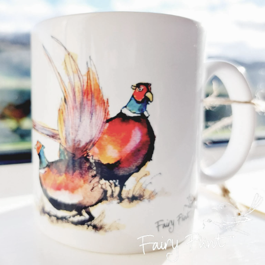 Ceramic mug with eco print of a fun Pheasant painting design by Fairy Flint photoshoot at Eaton Manor Shropshire, Wenlock Edge behind the mug